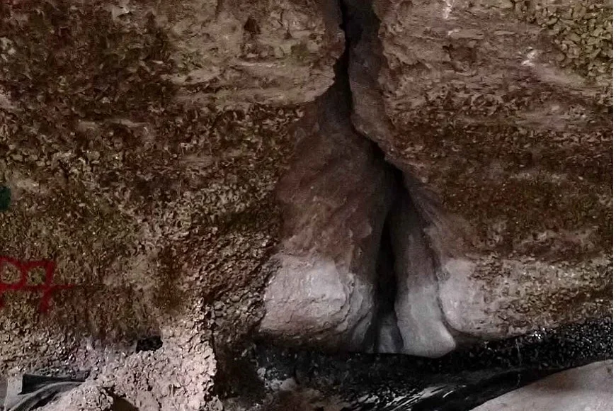 Das Bild zeigt eine Spalte (Riss) in weißgrauem Steinsalz. Unter der Spalte ist eine schwarze Folie verlegt. (Salz-)Wasser fließt aus der Spalte auf die Folie.
