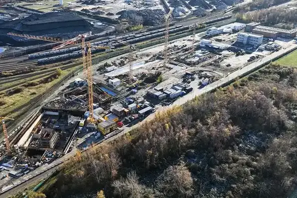 Die Luftaufnahme der Schachtanlage Konrad 2 zeigt ein im Bau befindliches Industriegelände mit weißen Gebäuden und mehreren gelben Drehkränen.