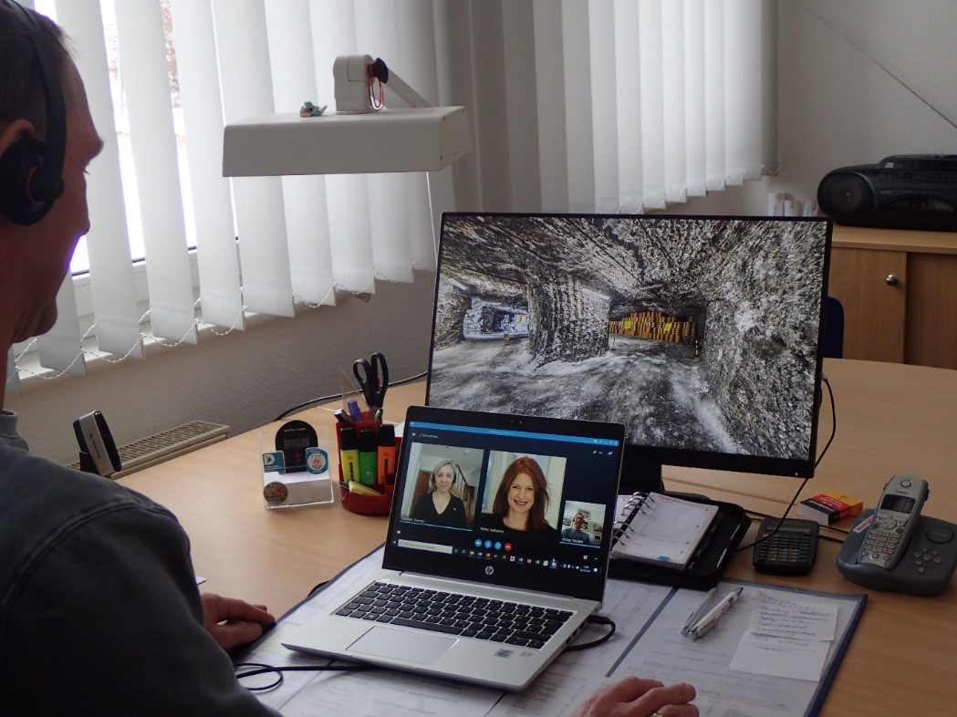 Eine Person sitzt vor zwei Bildschirmen und nimmt an einer Videokonferenz teil