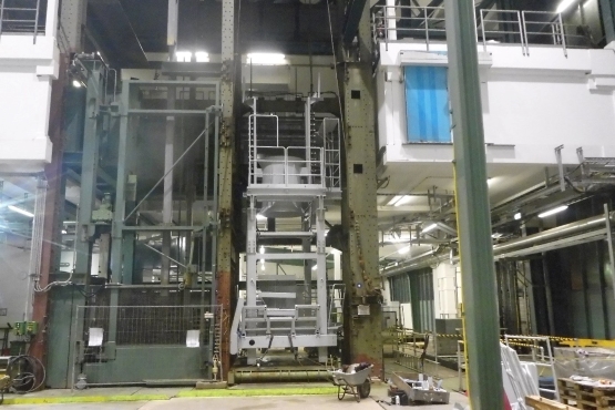 Das Bild zeigt die Schachthalle auf Konrad 1 mit dem grün gestrichenen Fördergerüst. Rechts daneben ist in hellgrau der obere Teil der neuen Arbeitsbühne zu sehen: Von der Metallkonstruktion sind die beiden oberen Decks sichtbar.