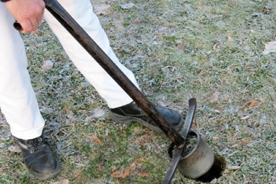 Eine Person hebt mit einem Ausstecher ein Stück Erde von zirka einem Kubikdezimeter aus dem Boden
