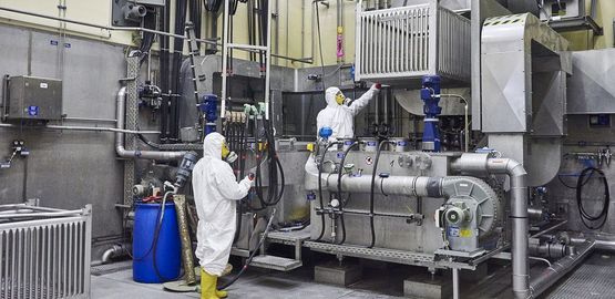 Employees decontaminate waste containers in an acid bath in an interim storage facility. Link to page "Treatment, packaging and storage"