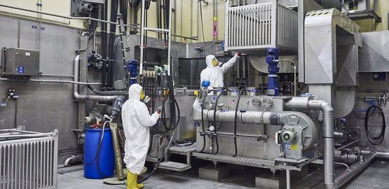 Arbeiter dekontiminieren im Zwischenlager Abfallbehälter in einem Säurebad. Zur Seite "Behandlung, Verpackung und Lagerung"