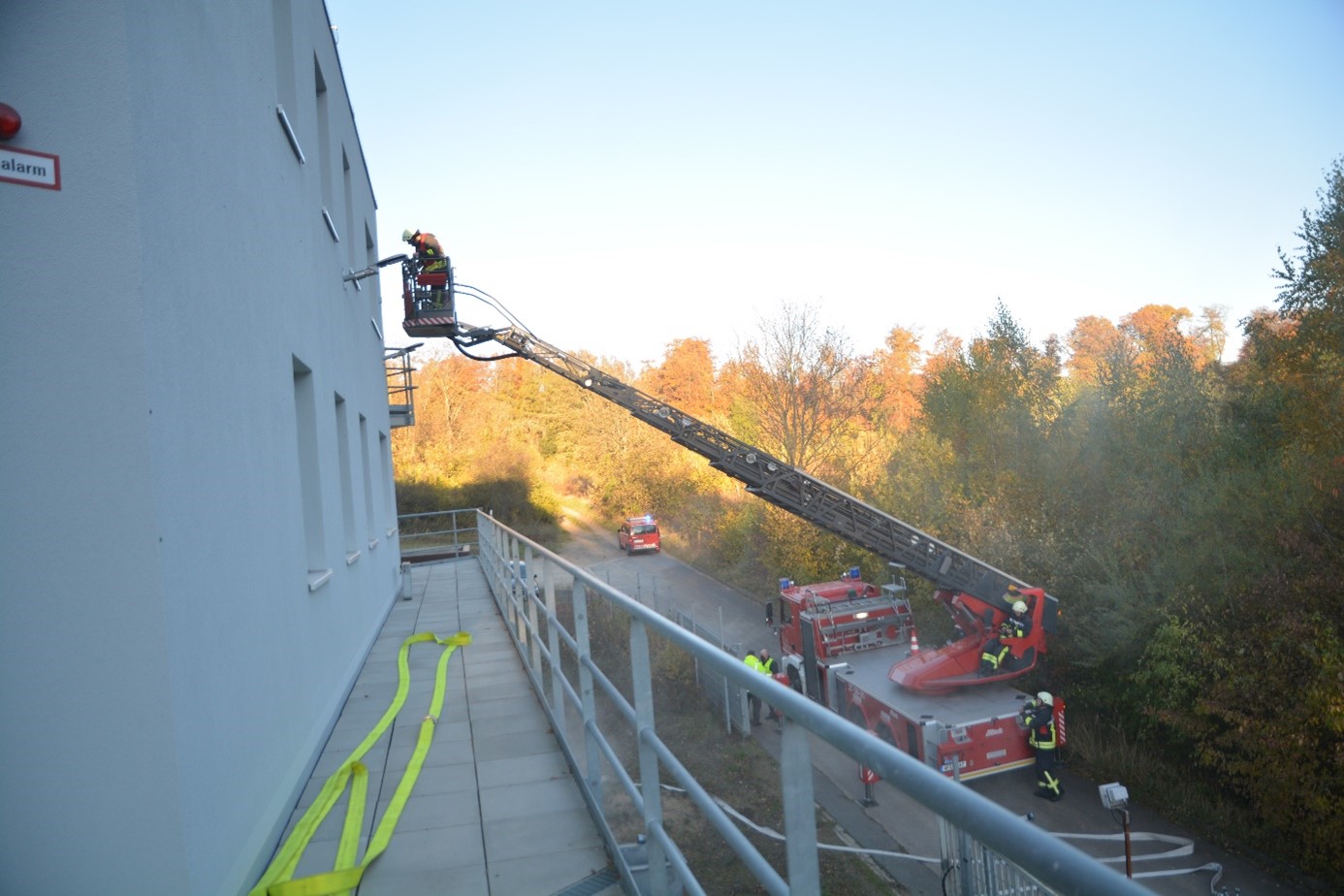 Die Drehleiter eines Feuerwehrautos steuert auf ein Dach zu.