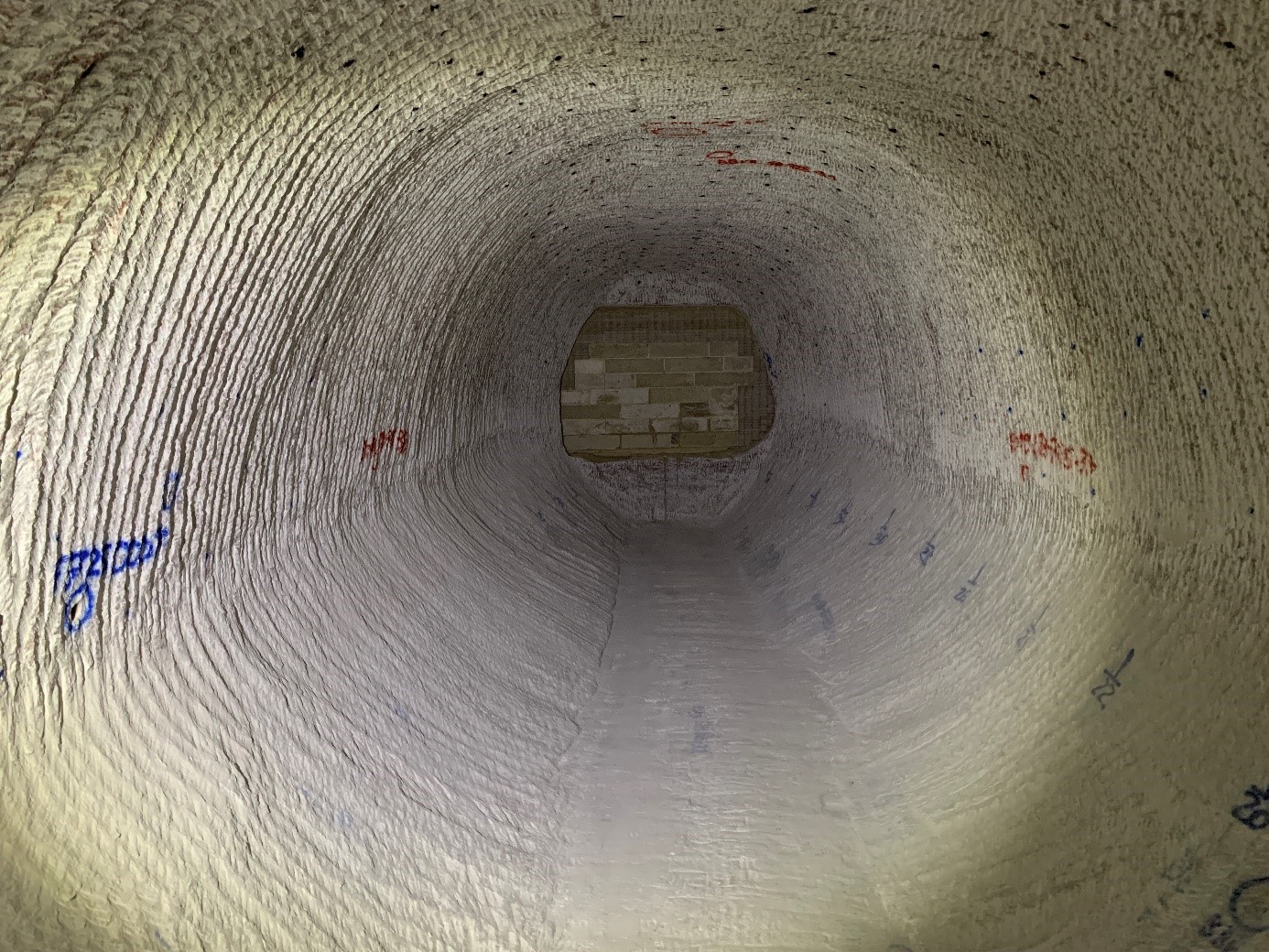 Das Foto zeigt eine oval geschnittene Strecke. Am gegenüberliegenden Ende befindet sich eine Mauer aus Spezialbeton. An den Wänden befinden sich Markierungen in blau und rot, die bei Vermessungsarbeiten als Orientierung dienen. 