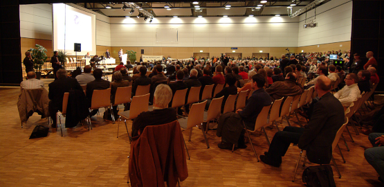 Publikum hört einem Vortrag zu. Zur Seite "Die Entscheidung zur Rückholung"