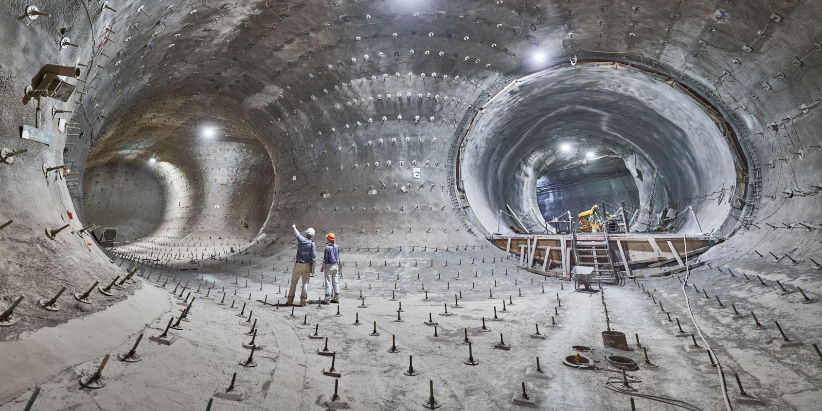 Zwei Personen stehen in Bergmannskluft in einem unterirdischen Tunnel.