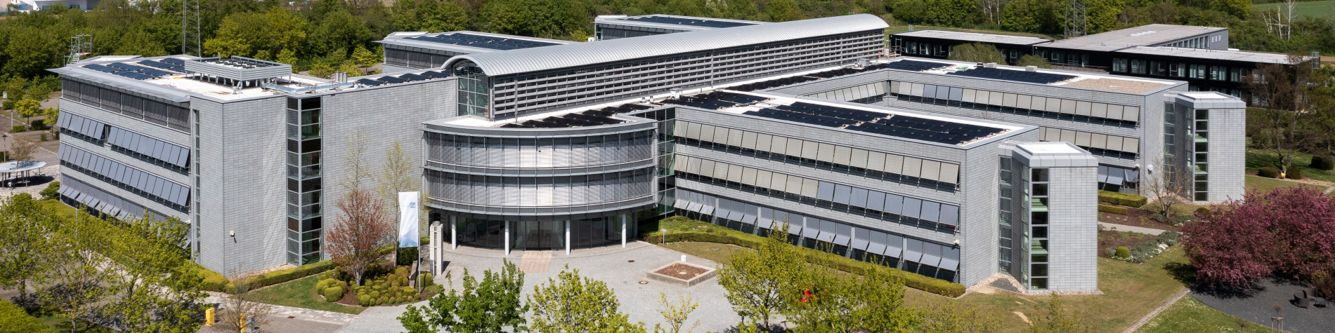 Diese Luftaufnahme zeigt das silbergraue Bürogebäude der BGE-Zentrale in Peine mit Bäumen.