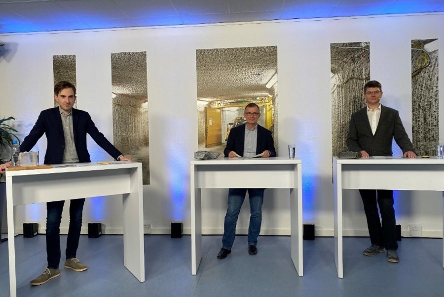 Drei Männer stehen nebeneinander an Stehtischen und sehen in die Kamera