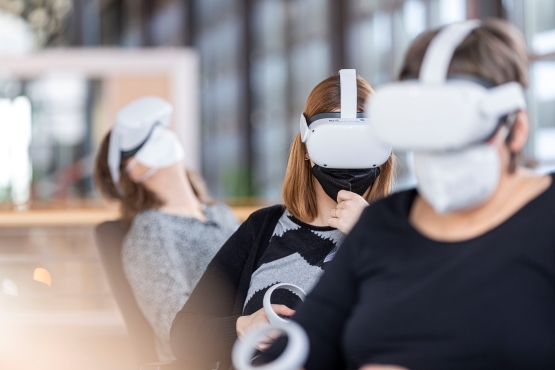Drei Personen mit weißen VR-Brillen und FFP2-Masken bei der virtuellen Erkundung des Endlagers Konrad.