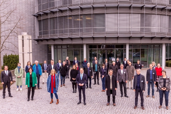 Eine Gruppe von Männern und Frauen steht vor einem Bürogebäude.