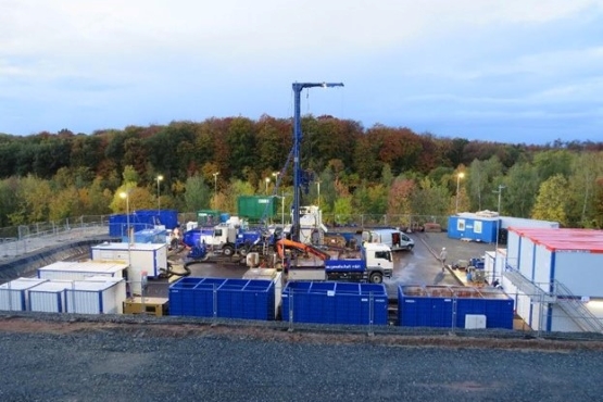 Auf dem Bild ist eine Baustelle mit Baucontainern, Baufahrzeugen und einem kleinen Kran abgebildet. Dies ist der Bohrplatz zur Erkundungsbohrung R10.