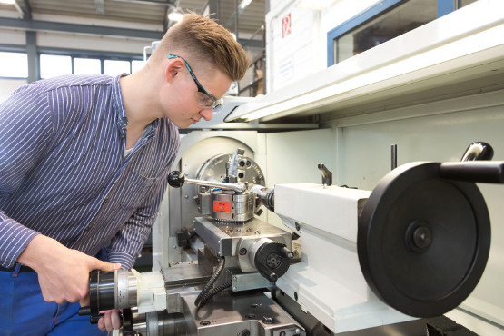 Ein Lehrling des Ausbildungsganges zum Industriemechaniker bearbeitet mit einer Fräsmaschine ein Werkstück.