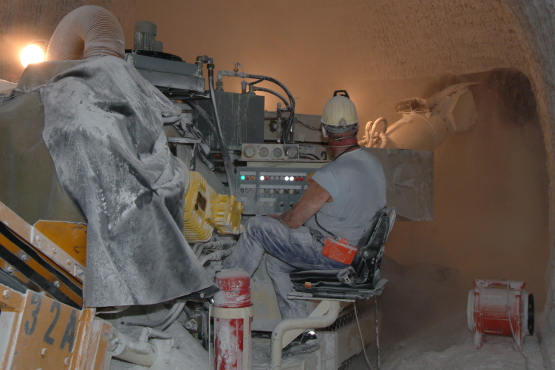 Ein Bergbautechnologe fräst mit einer Maschine unter Tage eine neue Strecke