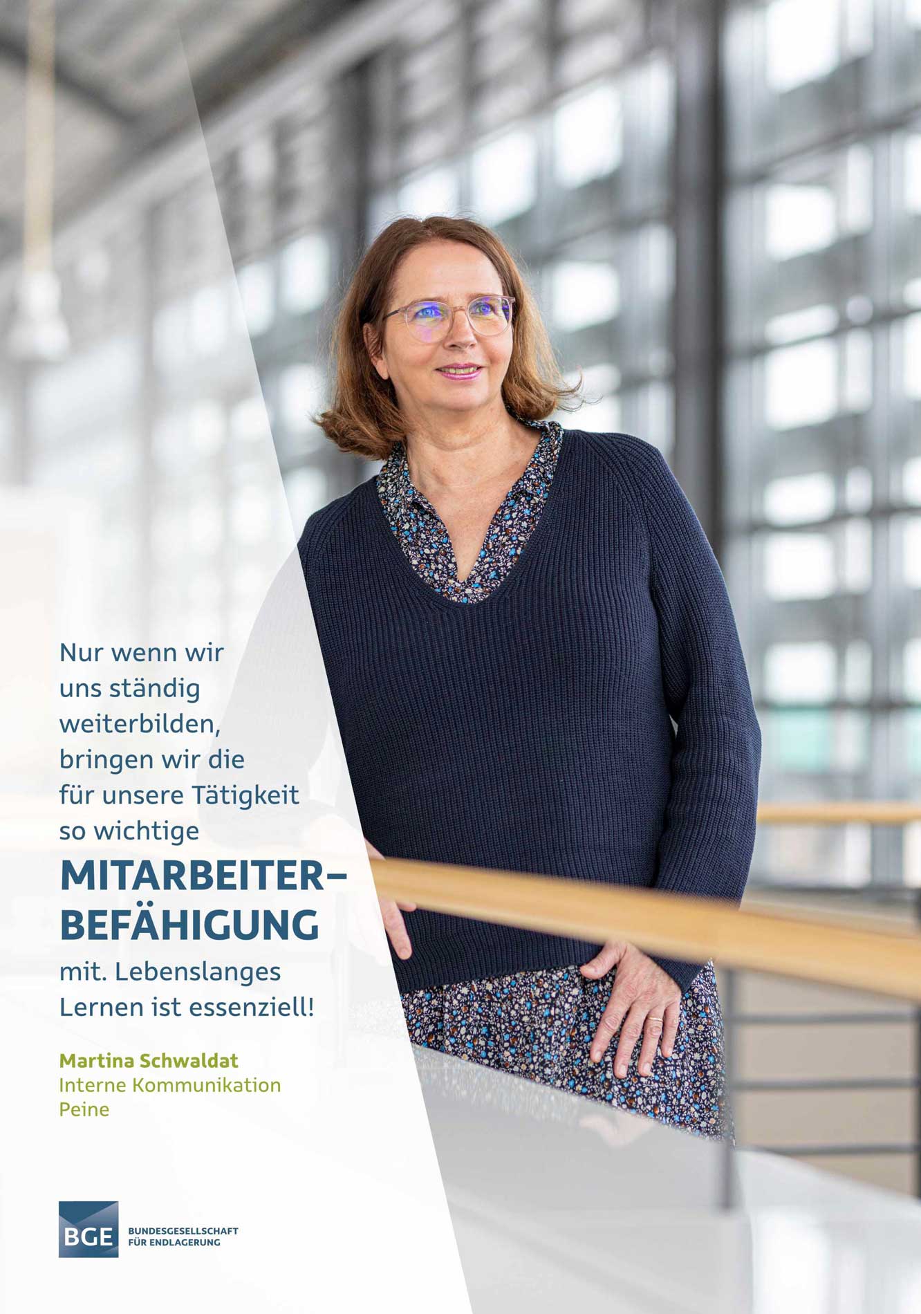 A woman with glasses is standing on the aisle of the BGE building.