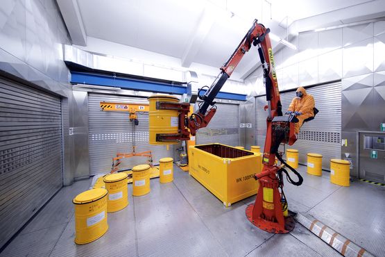 A worker loads waste barrels into a container