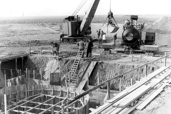 Die historische Aufnahme zeigt Arbeiter, die mit einem Kran am Schacht Konrad 1 arbeiten