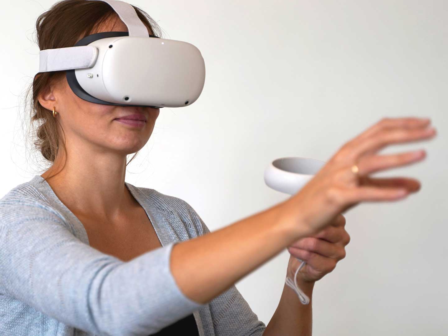 VR-Brille im Einsatz Eine Frau mit VR-Brille auf dem Kopf und Controller in der Hand