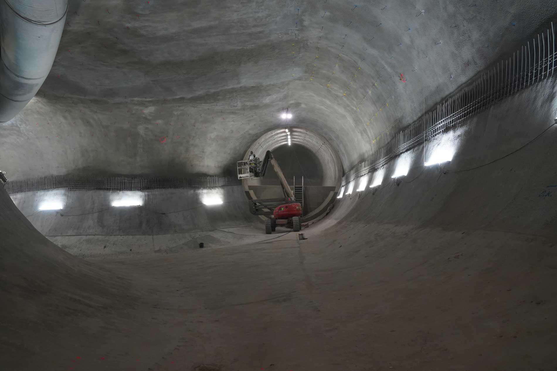 Ein Arbeiten auf einem Hubsteiger arbeitet am Einbau einer Inneschale eines Grubenraumes. Der untere Teil ist bereits fertig.