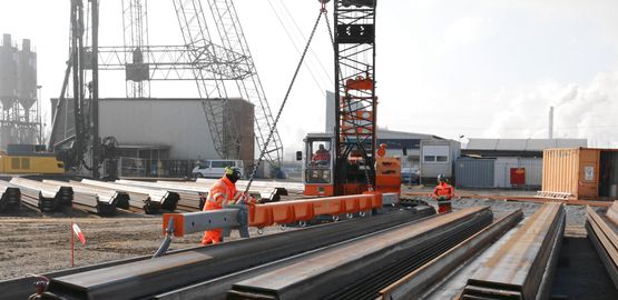Construction workers unload sheet piles with a crane