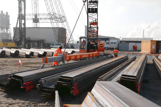 Construction workers unload sheet piles with a crane