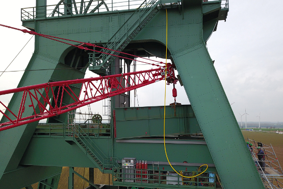 Ein Kran platziert einen neuen Stahlträger am Förderturm.