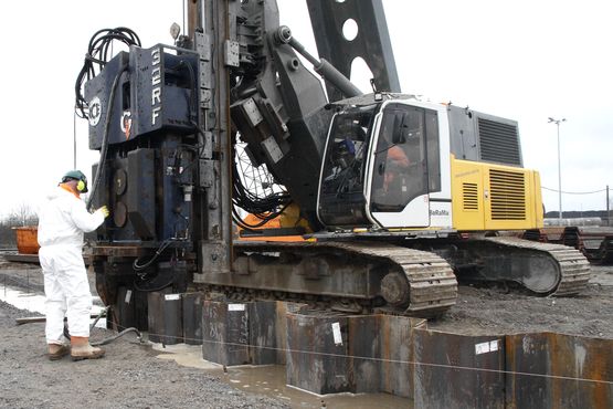 Ein Bagger rammt Spuntwände in die Erde 