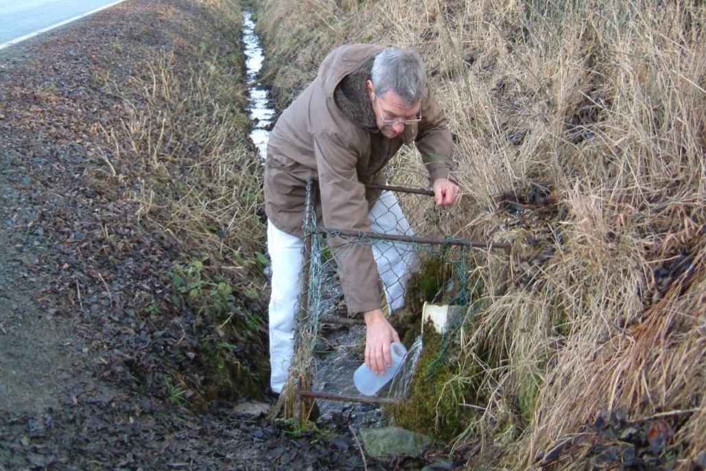 Ein Mann fängt mit einem Behälter Wasser auf. 