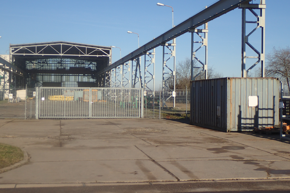 Ein Großcontainer steht vor dem Zaun des übertägigen Kontrollbereichs 