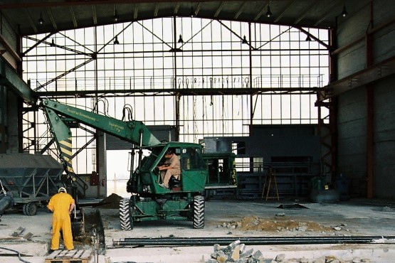 Ein Bagger hebt in der Containerhalle eine Grube für die Verlegung von Rohrleitungen aus