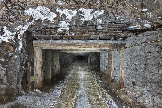 Altbergbau in der Schachtanlage Marie Ein Tunnel im Salzgestein unter Tage. Eine Holzkonstruktion besthend aus senkrechten und waagerechten Holzbalken stützt einen Teil der Decke des Tunnels.