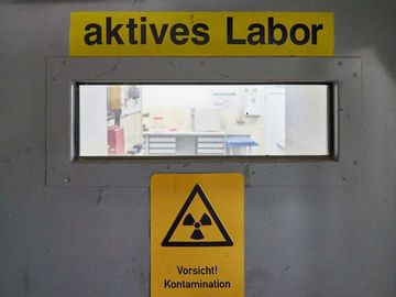 Großaufnahme eines Türausschnitts mit der Aufschrift "Aktives Labor". Zur Seite "Betriebliche Sicherheit und Strahlenschutz"