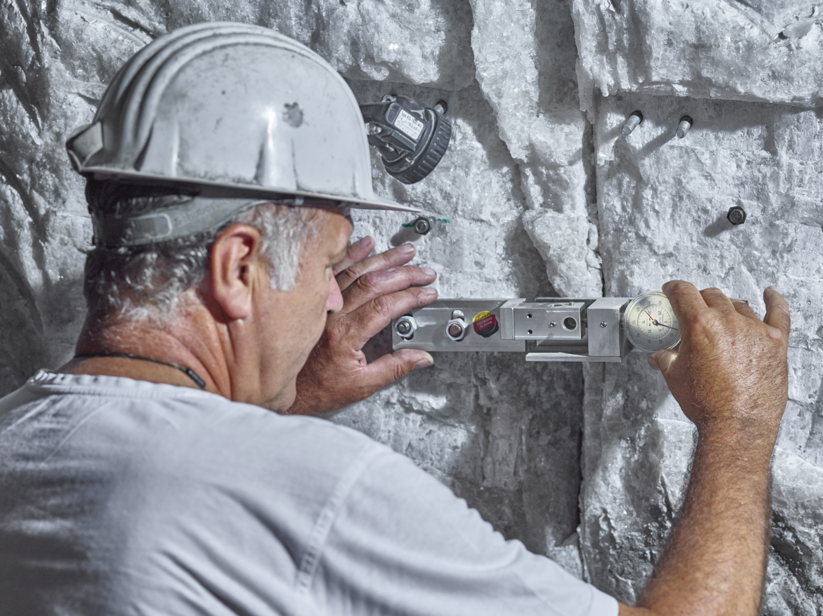 Mitarbeiter kontrolliert einen Riss im Bergwerk mit einem Fissurometer