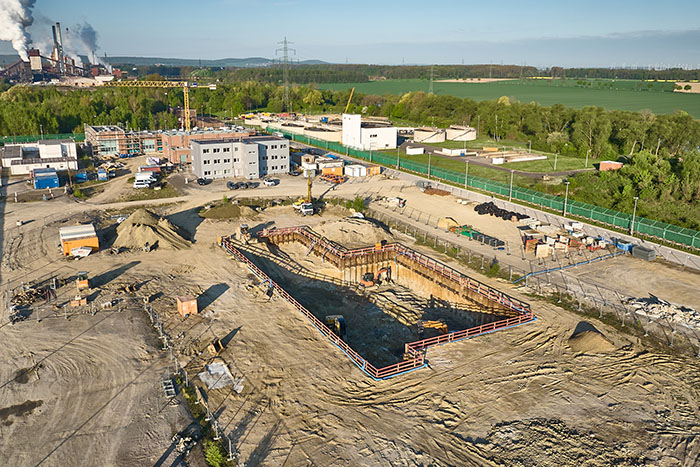 Construction pit in green landscape, power plant in the background
