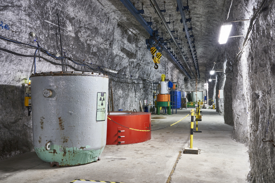 Im Untertage-Messfeld sind mittelradioaktive Cobalt-60 Strahlenquellen in speziellen Bohrlöchern zwischengelagert Streckenabschnitt mit Kranbahn und Ausrüstungsteilen, ein Bohrloch ist erkennbar